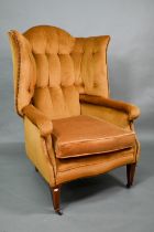 An antique button and wing backed armchair raised on square tapering front legs to ceramic