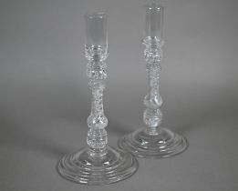 A pair of antique glass candlesticks with plain cylindrical sockets on baluster stems with bubbles