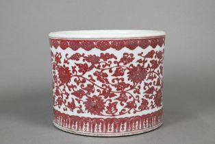 A Chinese red and white cylindrical jardiniere, painted in underglaze copper red with a wide band of