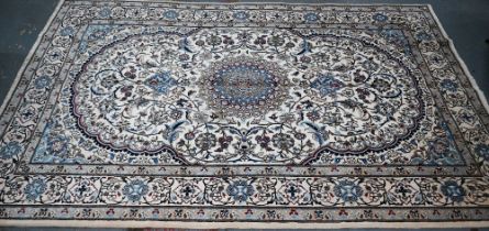 A central Persian Nain carpet of classical floral garden design, executed in blues, brown on camel