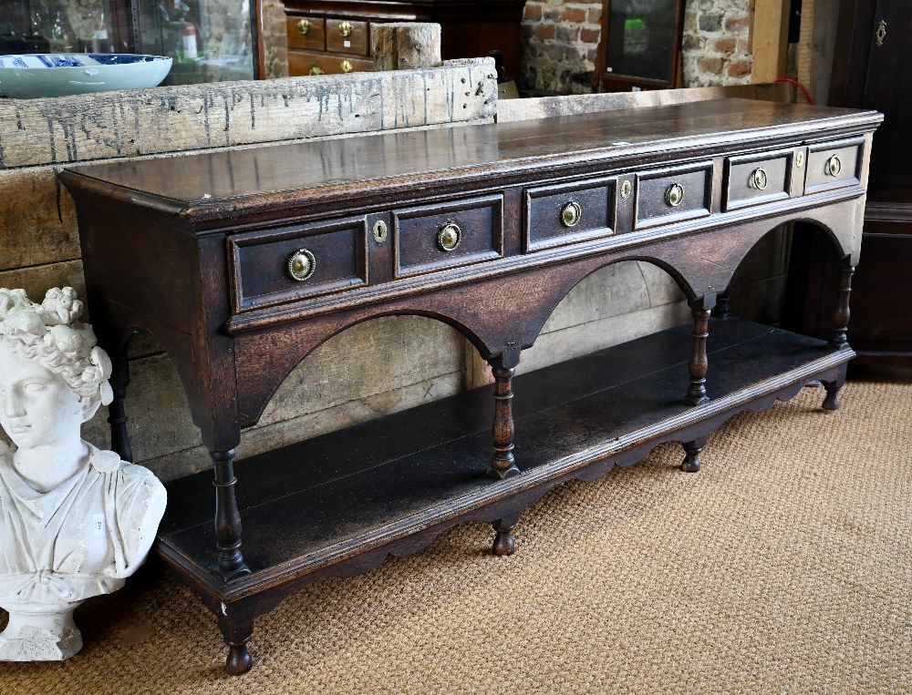 An antique oak low dresser with three double moulded front drawers over a triple arched apron,