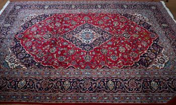 A contemporary central Persian Kashan carpet, the red and blue ground with floral vines centred by a
