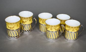 An Edwardian set of six Spode yellow and gilt coffee cans, in pierced silver holders with scroll