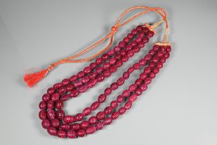 A triple row of graduated carved ruby beads on silk cord, 1 x 0.8 cm the smallest, 1.5 x 1.3 cm