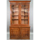 A late Victorian mahogany library cabinet bookcase, the pair of arched glazed doors over a