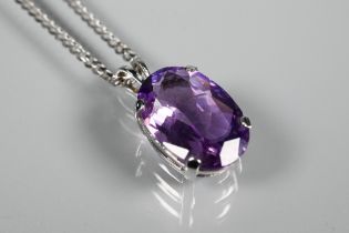 An oval amethyst pendant in claw setting on flat linked white metal chain stamped 750, approx 5.