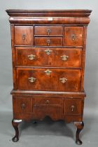 A Queen Anne period and later altered feather banded walnut chest on stand, the moulded cornice over