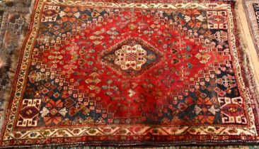 An old Persian Shiraz rug, the red ground of stylised flowers centred by a medallion, 160 cm x 114