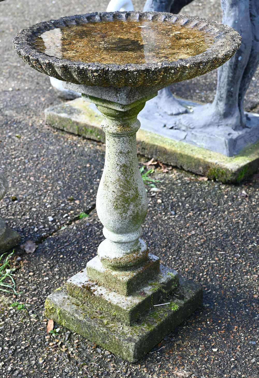 A weathered cast stone column bird bath