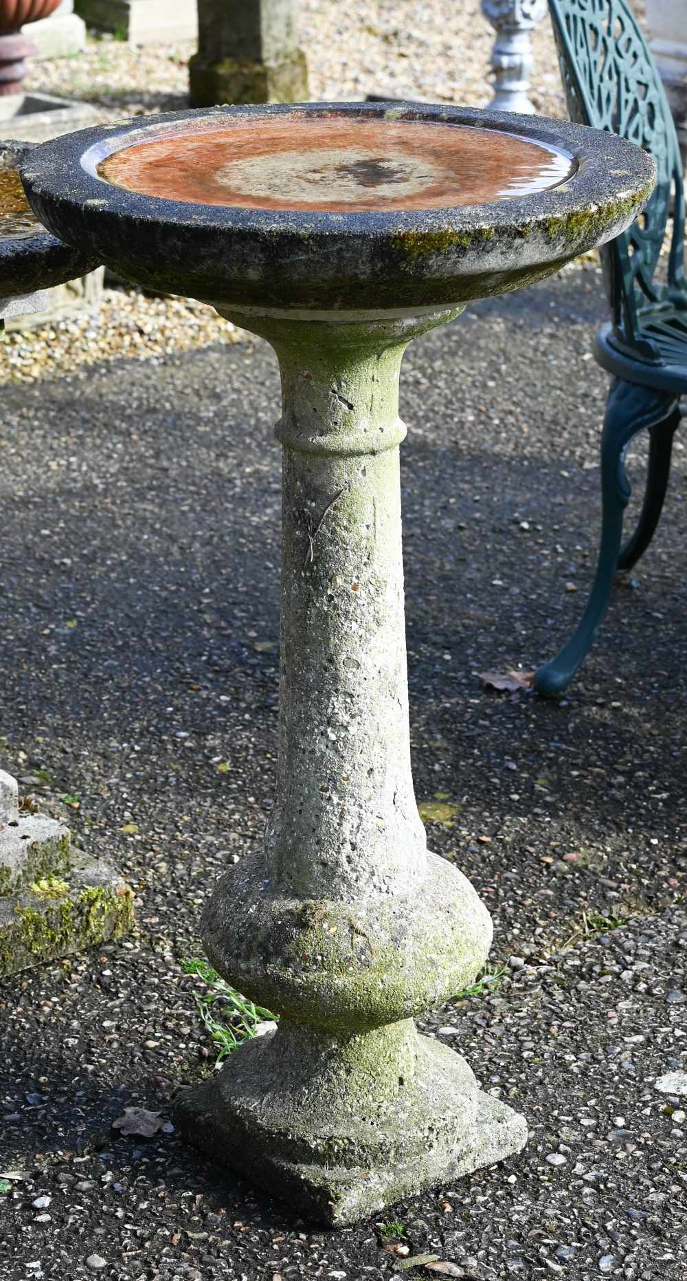 A weathered cast stone column birdbath