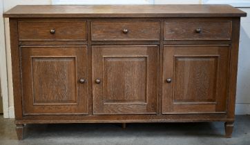 A Multiyork limed oak sideboard with three drawers over panelled cupboards, on tapering square