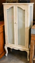 A French cream painted cabinet with glazed doors and side panels, shelved interior, cabriole