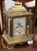 A 19th century French heavy brass mantel clock with ornately decorated dial and side panels, the