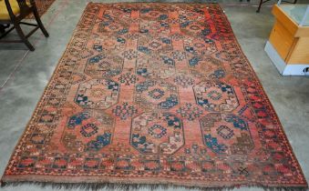 A worn Afghan carpet, with rows of large octagonal guls on red ground, with geometric border, 320