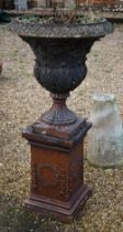 A large weathered classical cast urn on plinth, with patinated teracotta surface finish, on square