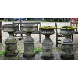 A pair of weathered cast stone garden planters raised on square plinths, to/with another pair, all