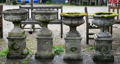 A pair of weathered cast stone garden planters raised on square plinths, to/with another pair, all