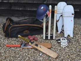 A cricket bag and contents, including two bats, pads, gloves and helmet, to/w a set of practice