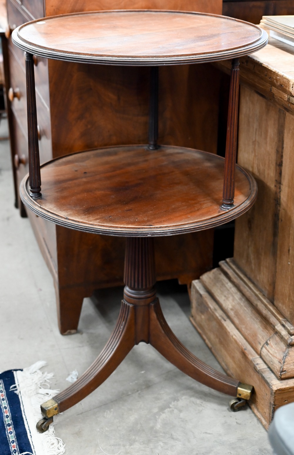 A Georgian mahogany twin-tier circular dumnb waiter on turned and reeded triform base with brass