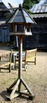 A traditional bird house/feeder on stand, with slate roof