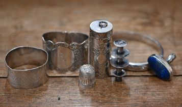 A .925 standard cotton spool in embossed cylindrical case, two silver napkin rings, an engraved