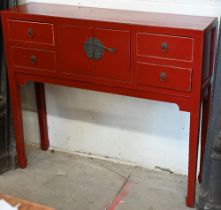 A Chinese red lacquer sidetable with central cupboards and two drawers to each side, with brass