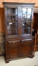 A reproduction oak cabinet bookcase, the top section with astragal glazed doors enclosing shelves on