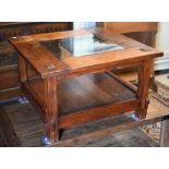 A rustic stained hardwood square coffee table with inset glass top and open under-tier, 80 x 80 x 50