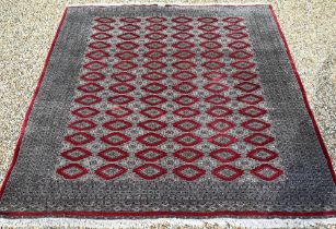 A large Pakistani Turkoman design carpet, red ground with repeating gul design and multi-borders,
