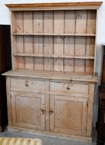 An antique stripped pine kitchen dresser with plate rack over two drawers and panelled cupboards,