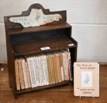 A selection of vintage Beatrix Potter books (a/f), in oak bookcase