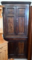 An antique stained pine corner cabinet with panelled doors and shelved painted interior, 202 cm high