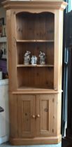 A waxed pine corner cabinet with open shelves above two panelled doors
