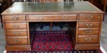 An early 20th century Victorian style twin-pedestal desk with green leather top over nine drawers,