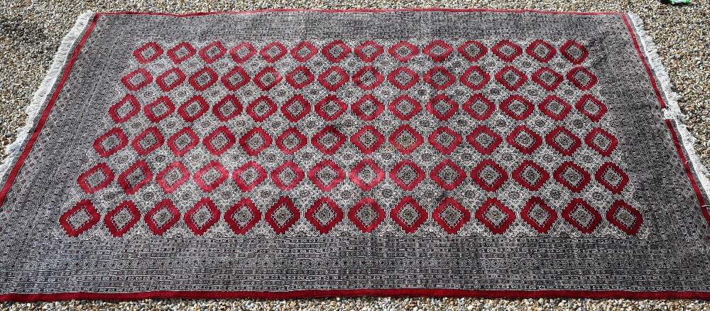 A large Pakistani Turkoman design carpet, red ground with repeating gul design and multi-borders, - Image 2 of 6