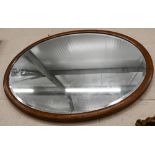 An Edwardian bevelled oval mirror in inlaid walnut frame, 103 cm wide x 78 cm high