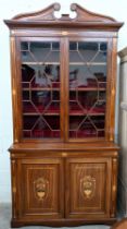 An Edwardian inlaid mahogany cabinet bookcase with swan-neck moulded pediment above twin glazed