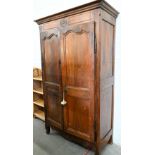 An antique French chestnut armoire with twin-panelled doors enclosing brass hanging rail (original