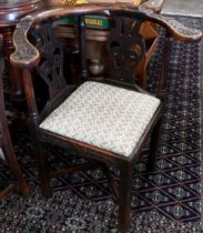 A 19th century carved oak corner chair with pad seat and chamfered square legs united by cross
