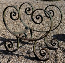 An antique wrought iron table base in remnants of green paint