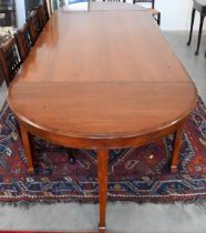 A large hardwood dining table on square supports with spade feet and central rectangular section,
