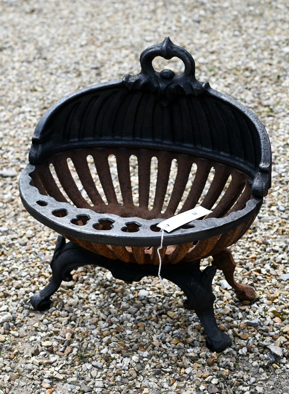An old oval cast iron fire basket, raised on scroll feet, 40 cm w