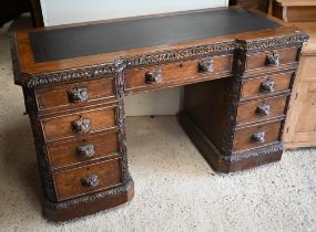 A late Victorian Gothic Revival carved oak twin pedestal desk with nine drawers and 'Green Man'
