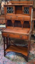 A 20th century Liberty style Arts & Crafts writing desk with leaded stained glass doors, three