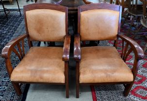 A pair of stained hardwood and tan leather open armchairs in the Art-Deco manner