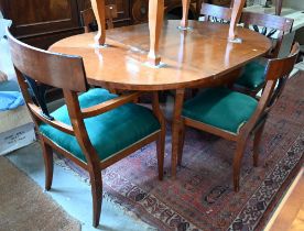 A Biedermeier circular fruitwood table, the top extending to accept one associated leaf to/w a set