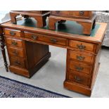 An Edwardian walnut twin pedestal desk with inset green leather top over nine drawers, 122 cm wide x