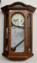 A German glazed oak wall clock with triple train movement chiming on five-rod gongs c/w pendulum and