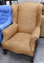 A wingback armchair covered in gold textured fabric, on cabriole supports