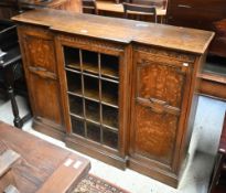 An oak breakfront bookcase with glazed central door flanked by panelled cupboards on plinth base,